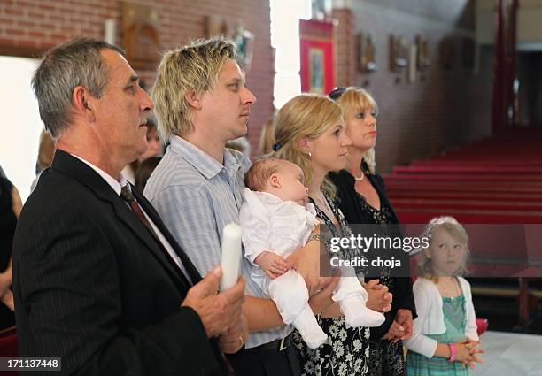 glückliche eltern und großeltern warten auf taufe für kleine jungen - catholic baptism stock-fotos und bilder