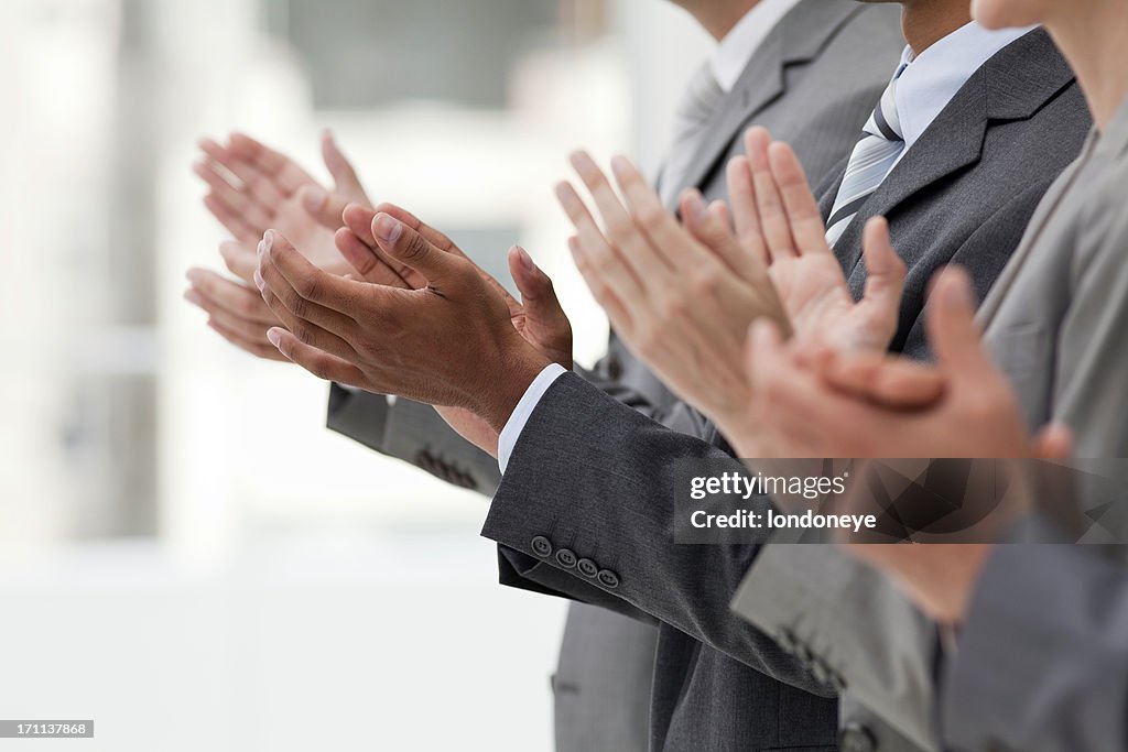 Row of clapping business executives.