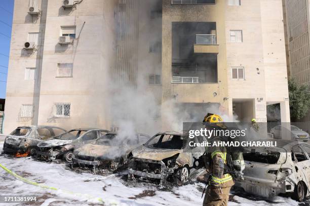 Israeli fire brigade teams douse the blaze in a partking lot outside a residential building following a rocket attack from the Gaza Strip in the...