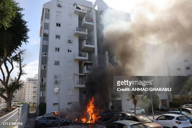 Cars parked outside a residential building catch fire during a rocket attack from the Gaza Strip on the southern Israeli city of Ashkelon, on October...