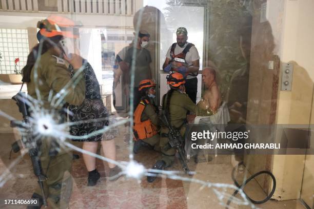 Israeli rescue teams tend to an elderly man seated on a chair in the entrance of a building that received a direct hit in Ashkelon during a rocket...