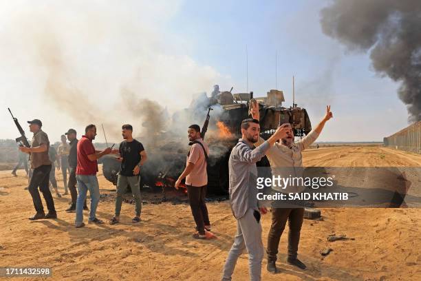 Palestinians take control of an Israeli Merkava battle tank after crossing the border fence with Israel from Khan Yunis in the southern Gaza Strip on...