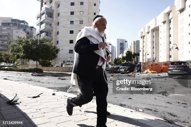 Man runs past cars damaged during a rocket attack in Ashkelon, Israel, on Saturday, Oct. 7. 2023. Israel declared a rare state of alert for war on...