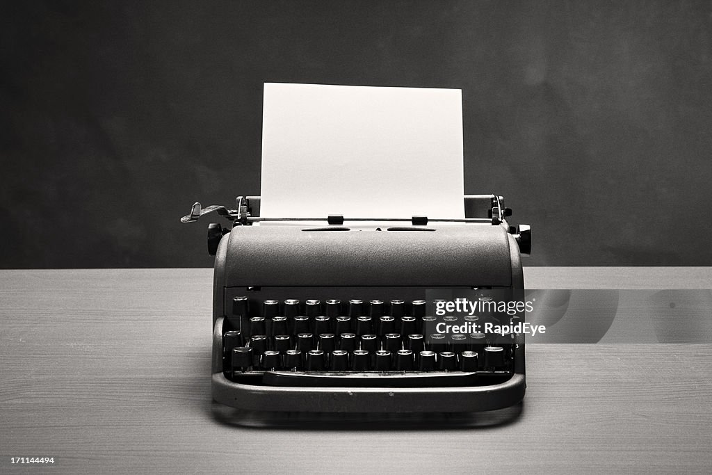 Moody film noir shot of vintage typewriter and blank paper