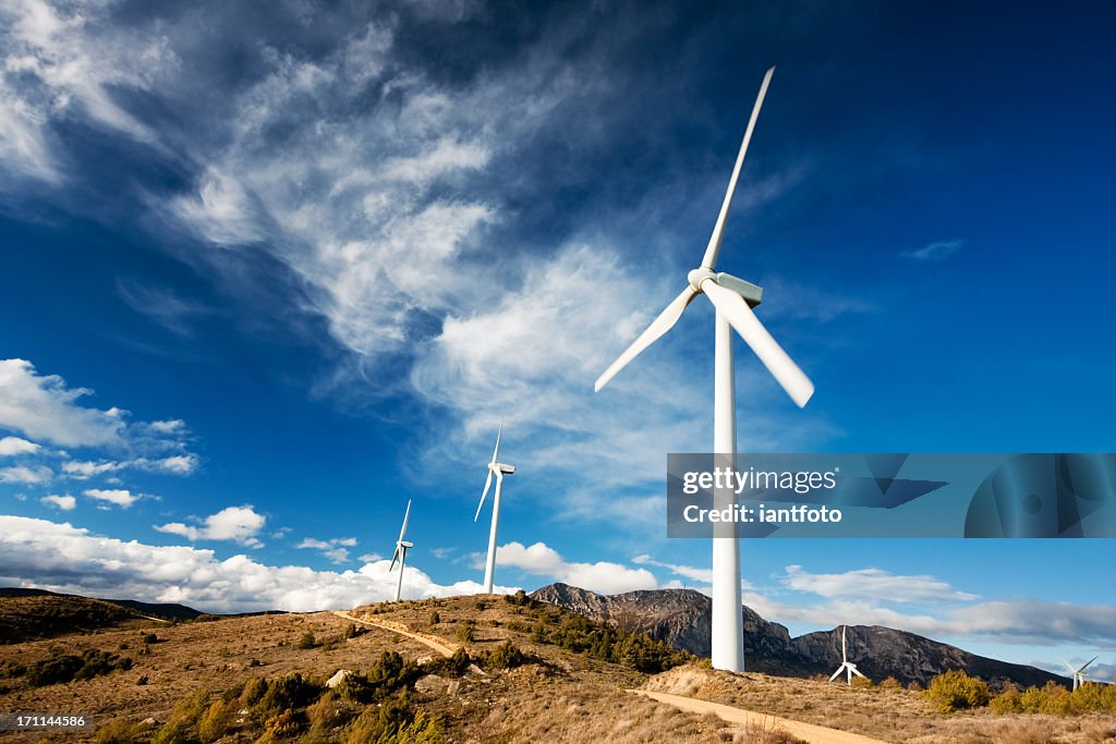 Row of white wind turbines in motion on a cloudy day