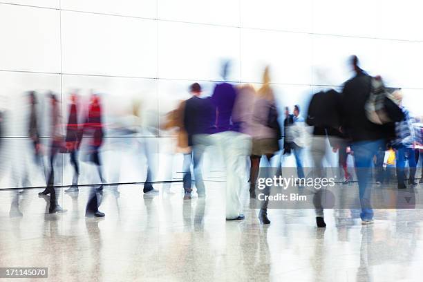 crowd of people walking indoors down walkway, blurred motion - large group of people white background stock pictures, royalty-free photos & images