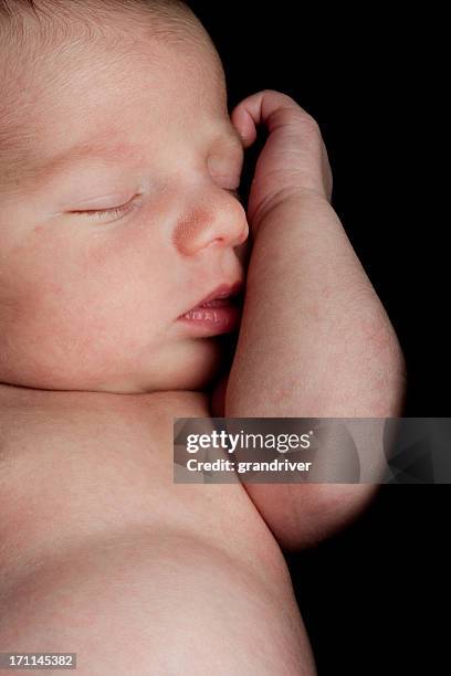 newborn baby boy isolated on black - gripping bedsheets stock pictures, royalty-free photos & images