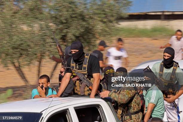 Palestinian militants move towards the border fence with Israel from Khan Yunis in the southern Gaza Strip on October 7, 2023. Barrages of rockets...