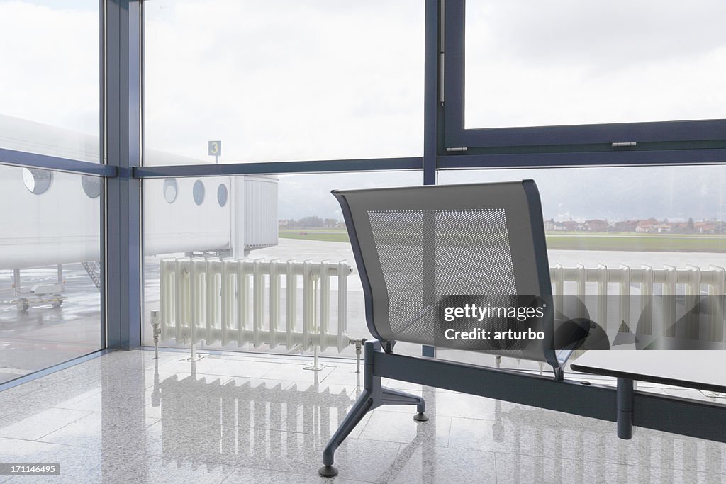 Área de espera do aeroporto com banco e Pista de Decolagem vista