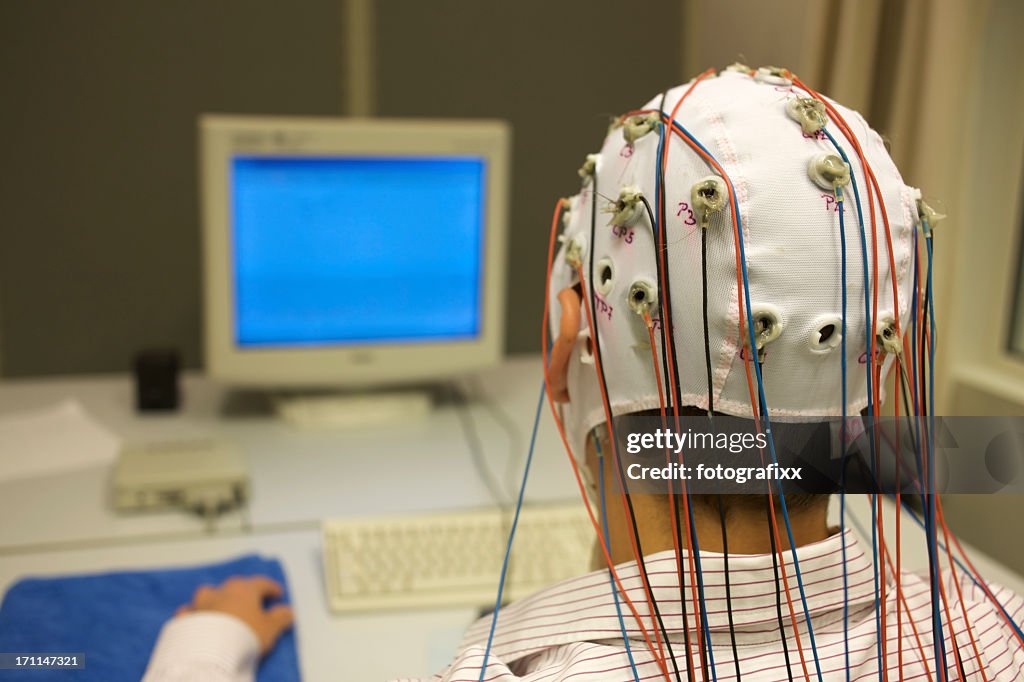 Homem ligadas com cabos para Eletroencefalograma na frente do monitor