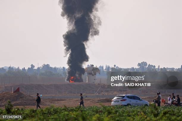 Picture taken from Khan Yunis in the southern Gaza Strip shows smoke billowing next to an Israeli observation tower on October 7, 2023. Barrages of...