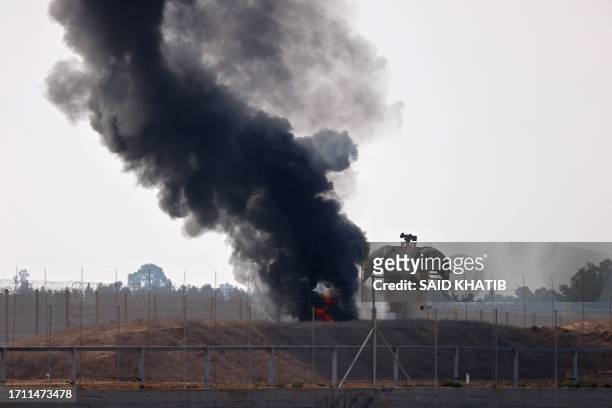 Picture taken from Khan Yunis in the southern Gaza Strip shows smoke billowing next to an Israeli observation tower on October 7, 2023. Barrages of...