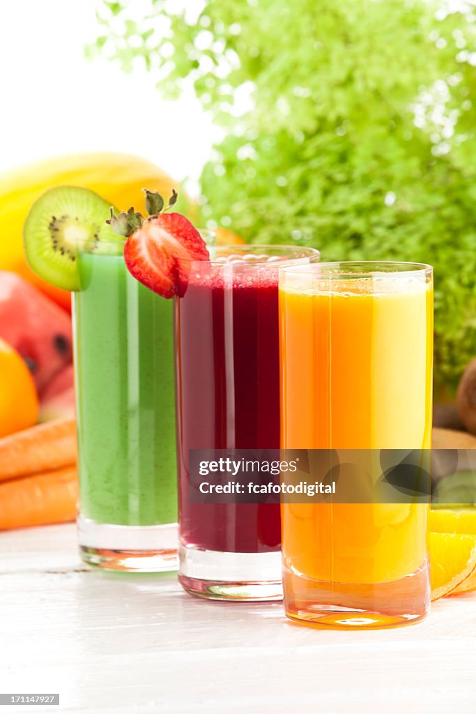 Three glasses of fruit juices on white garden table