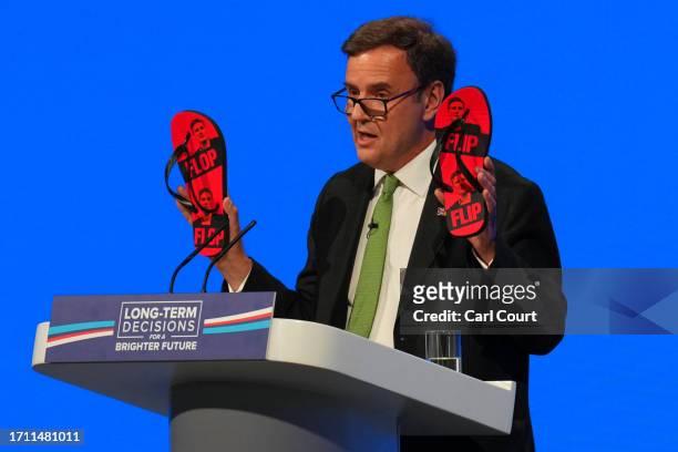 Greg Hands MP, Chairman of the Conservative Party holds up some flip-flops with the image of Labour leader Keir Starmer on them as he gives a speech...