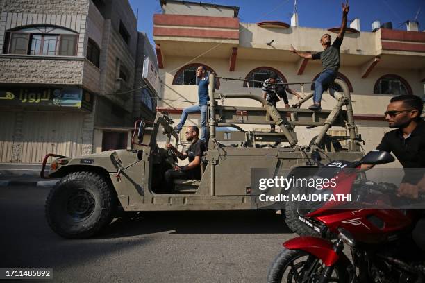 Palestinians return to Gaza City driving an Israeli Humvee that was seized after militants entered Israel by land on October 7, 2023. Barrages of...