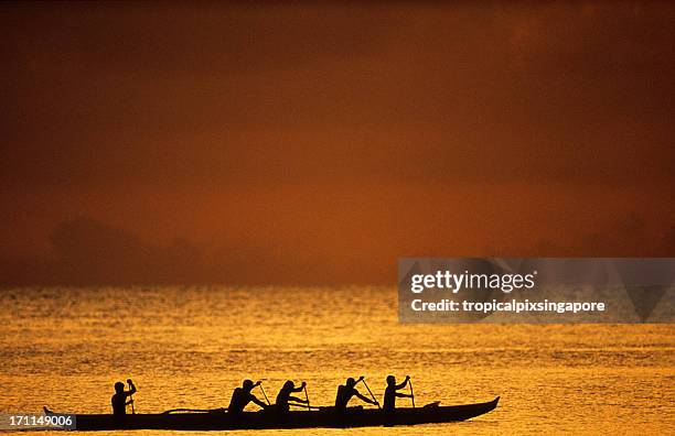 silhouette of rowers at sunset in oahu, hawaii's north shore - outrigger stock pictures, royalty-free photos & images