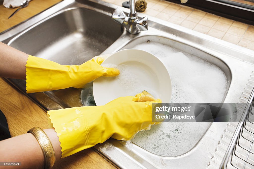 View over shoulder of young woman doing the dishes