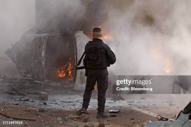 Member of the security forces next to a burning car following a rocket attack in Ashkelon, Israel, on Saturday, Oct. 7. 2023. Israel declared a rare...
