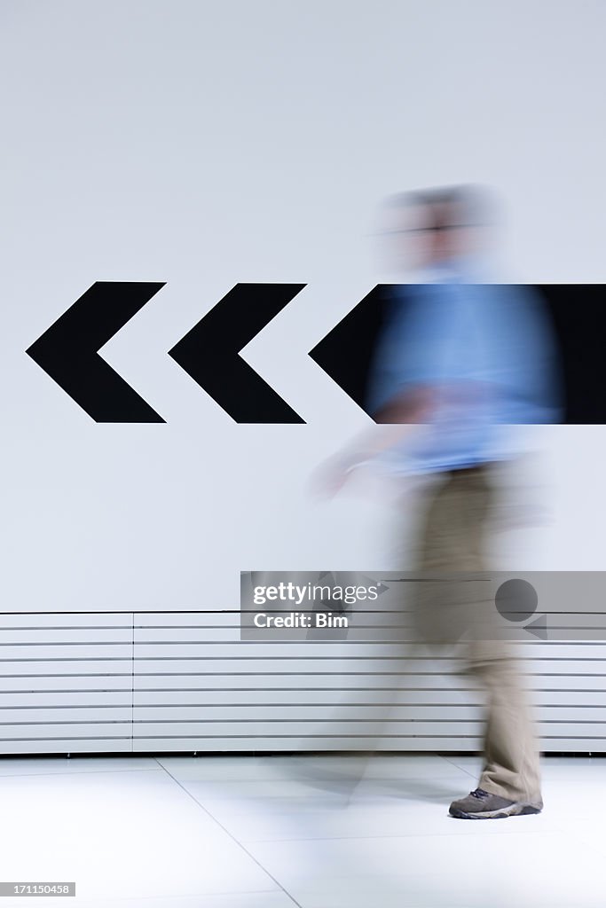 Man walking in opposite direction of arrow