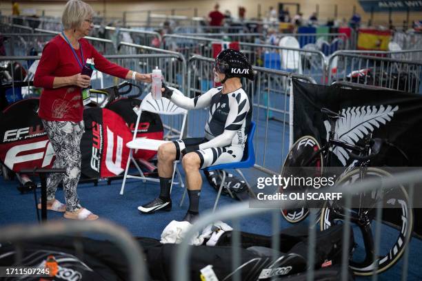 Colin Claxton , of New Zealand, receives a drink after competing in the semifinals for the Men's Sprint in the age 75+ categories at the UCI Masters...