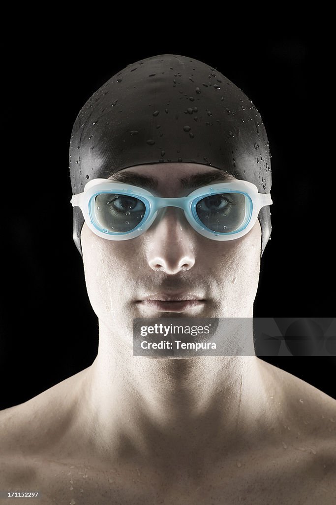 Swimmer on black with cap and goggles, male.