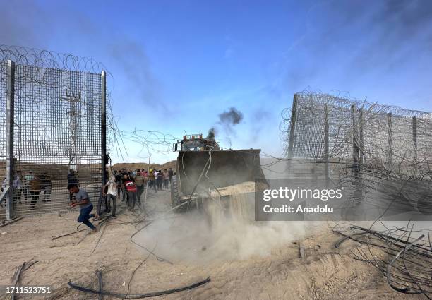 Palestinians groups break over a fence with the help of a digger as the clashes between Palestinian groups and Israeli forces continue in Gaza City,...