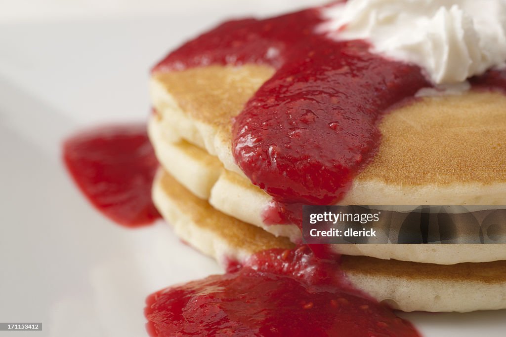 Small stack of three pancakes with raspberry sauce