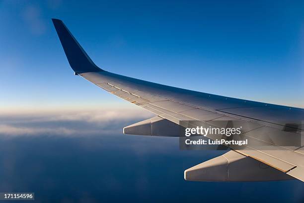 airplane wing above the clouds during flight - vliegtuigvleugel stockfoto's en -beelden