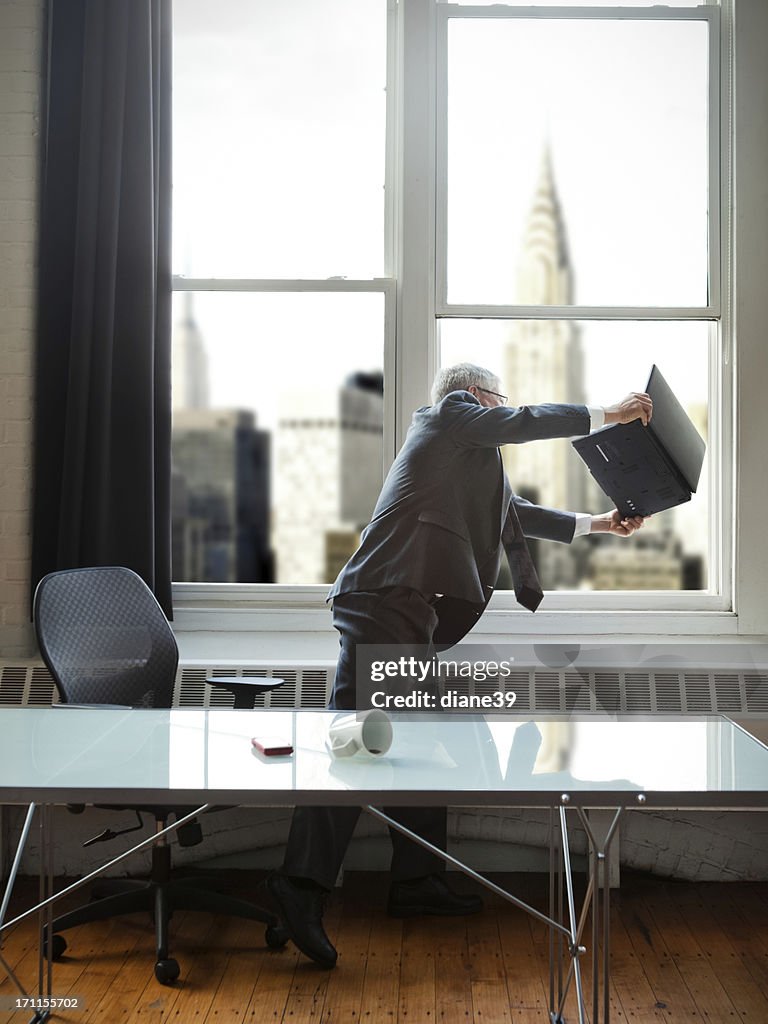 Frustrated businessman throwing a laptop out the window