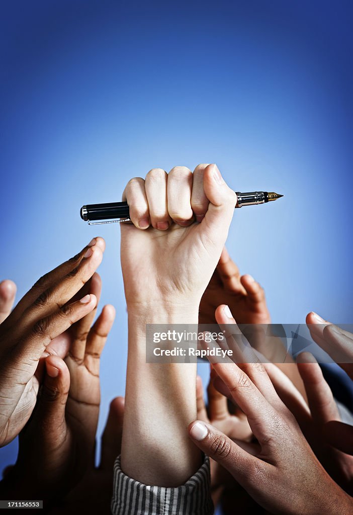 Power of communication: one spotlit hand holds up a pen