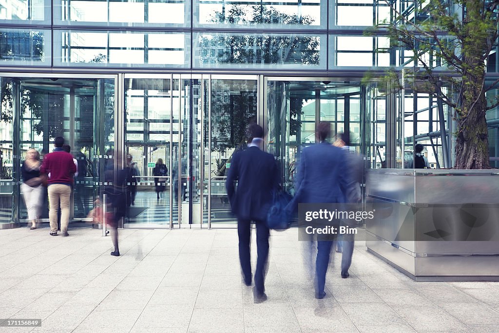 Las personas de negocios de ingresar y salir de edificio de oficinas, desenfoque