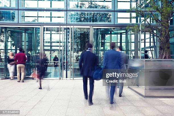 business people entering and leaving office building, motion blur - betreden stockfoto's en -beelden