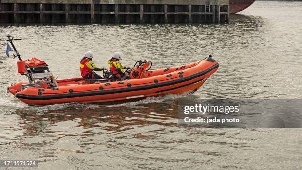 orange lifeboat with two crew members - 救命ボート ストックフォトと画像