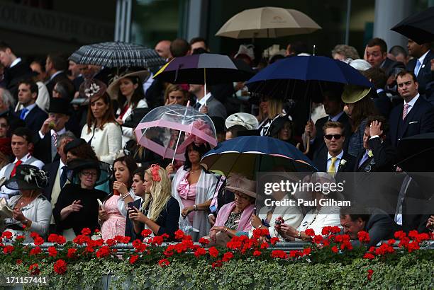 Racegoers look on under umbrellas as the rain starts to fall during day five of Royal Ascot at Ascot Racecourse on June 22, 2013 in Ascot, England.