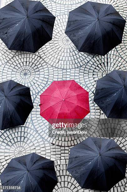 un parapluie rouge entourée de parasols noir - umbrellas from above photos et images de collection