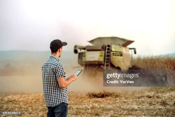 young farmer with digital tablet controlling corn harvest - may 19 stock pictures, royalty-free photos & images