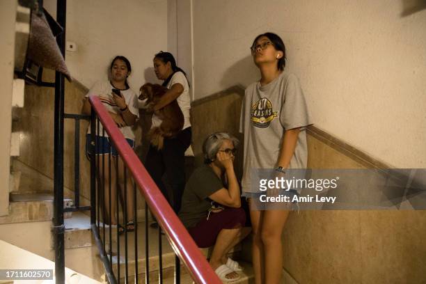 People hide in a building staircase as sirens are heard in on October 7, 2023 in Tel Aviv, Israel. Israel's Defense Forces say that Hamas "had begun...