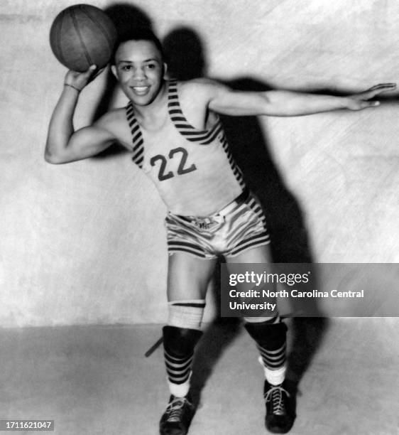 James Hardy posing for photograph while holding basketball on the court.