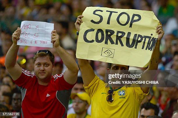 Spectators show posters against corruption as they wait for the start of the FIFA Confederations Cup Brazil 2013 Group A football match between Japan...