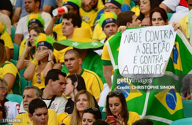Spectator holds a poster to protest against corruption as she waits for the start of the FIFA Confederations Cup Brazil 2013 Group A football match...