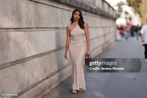 Angelica Burgos is seen outside Elie Saab show wearing a nude shiny Hanae Clothes dress with asymmetrical upper part, wine red Lady Dior handbag and...