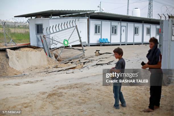 Youths stand by a crater following an Israeli airstrike at the Erez crossing between Israel and the northern Gaza Strip, on October 7, 2023....