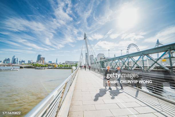 pedestrians crossing on hungerford bridge golden jubilee bridges london uk - day anniversary stock pictures, royalty-free photos & images