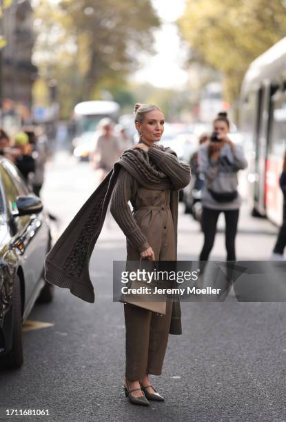 Leonie Hanne is seen outside Hermes show wearing silver earrings, taupe knit scarf, matching sweater and matching leather overall, brown Hermes...