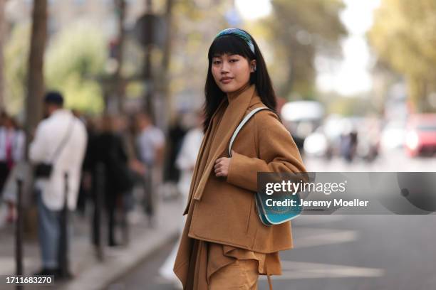 Jihoon Kim is seen outside Hermes show wearing blue head band, camel colored cropped Hermes jacket, matching shirt and oversized camel colored cargo...