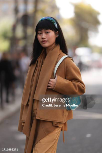 Jihoon Kim is seen outside Hermes show wearing blue head band, camel colored cropped Hermes jacket, matching shirt and oversized camel colored cargo...