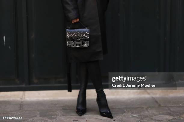 Caro Daur is seen outside Hermes show wearing a full Hermes look, black leather coat, a black silver studded Hermes Constance handbag and black heels...