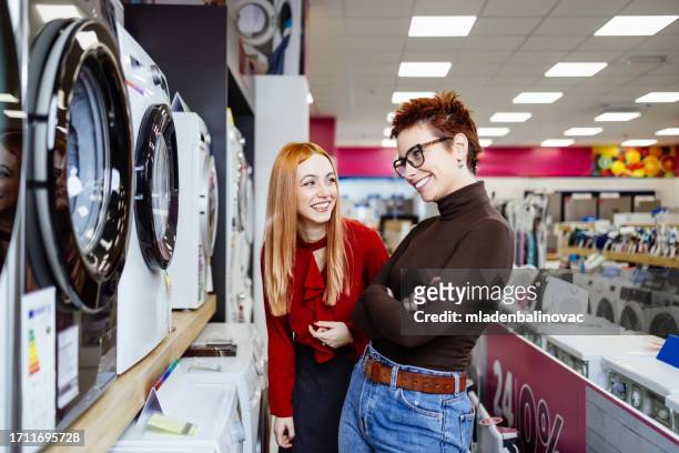 lgbt couple buying home equipment in electronic store - buying washing machine stockfoto's en -beelden