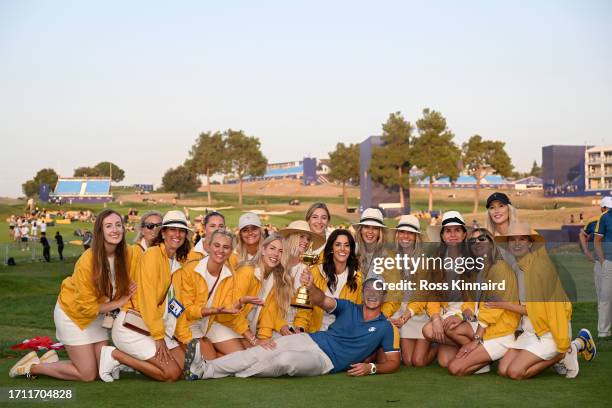 Viktor Hovland of Team Europe poses for a photograph with the Ryder Cup trophy alongside the partners of Team Europe teammates following the Sunday...