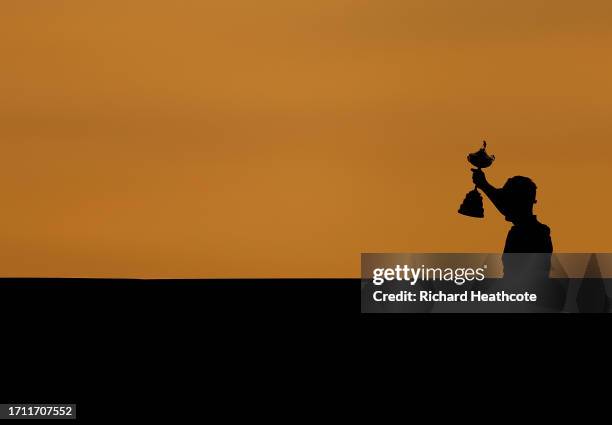 Team Europe Captain Luke Donald lifts the trophy as he walks over the player bridge after Europe secure victory in the Sunday singles matches of the...